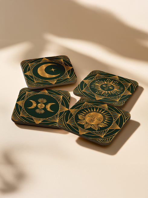 A set of four square coasters with a glossy finish, featuring celestial gold designs on a deep forest green background. Each coaster showcases a unique motif: a stylized sun with a serene face, a crescent moon with a star, a triple moon symbol with botanical elements, and a radiant sunburst. The intricate gold linework creates an art deco-inspired, mystical aesthetic. Made from durable materials, these coasters blend elegance with celestial charm.